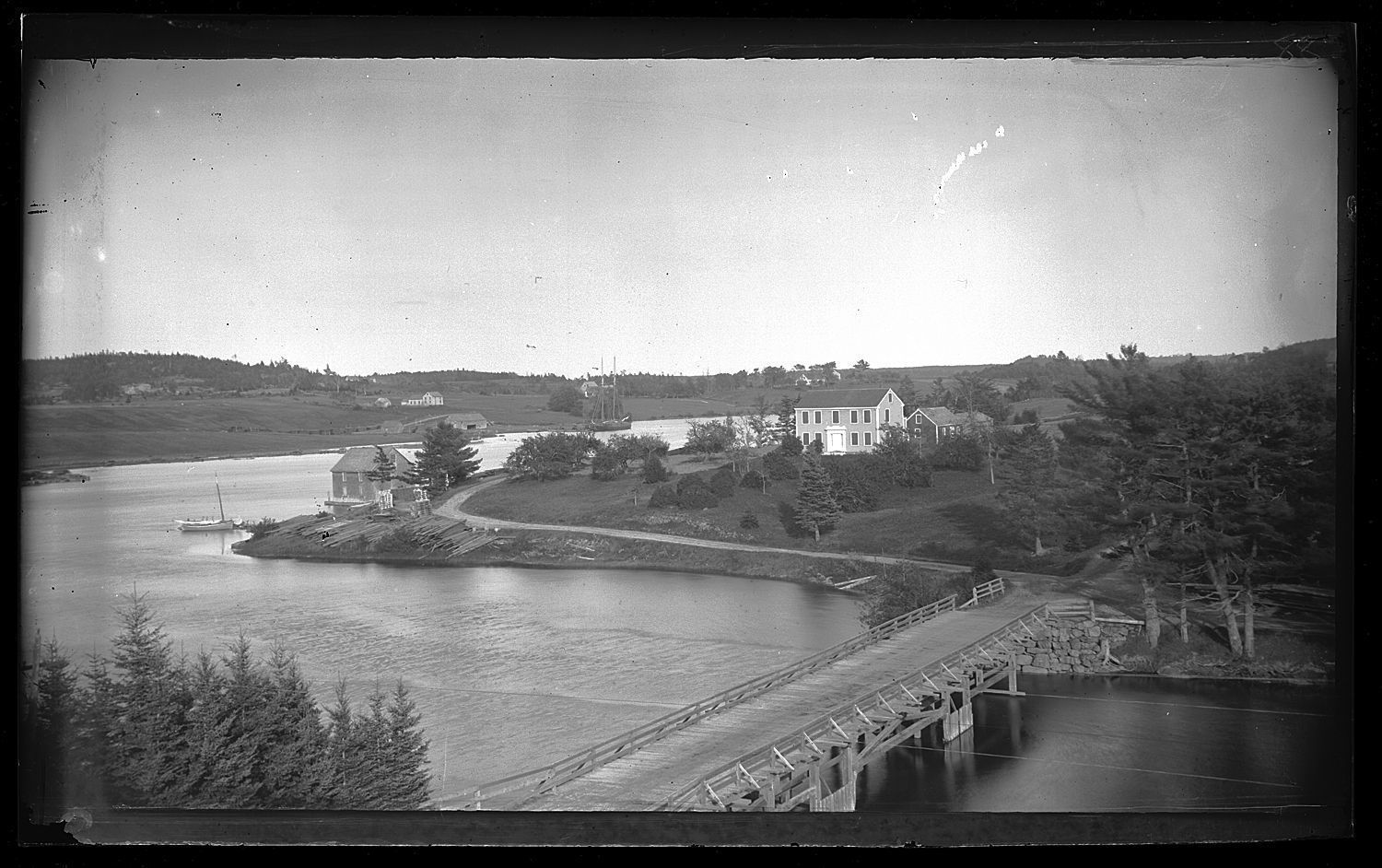 Boats, wharves and houses on the Dennys River, c. 1880; Aaron Hobart's house in Edmunds dominates this a view from the belfry of the Congregational Church in Dennysville. The Lower Bridge links the two towns, while the warehouse and lumber beside Allan's wharf and the schooner and houses along Fosters Lane on the distant shore testify to the prosperity the communities in the late nineteenth century. Photograph by Dr. John P. Sheahan of Edmunds.