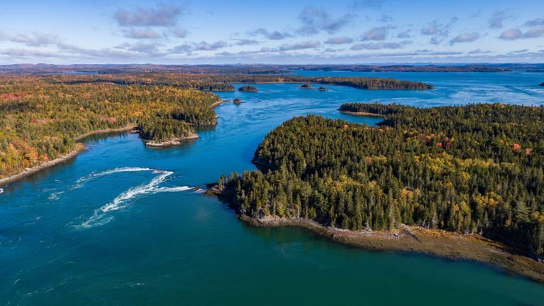          Reversing Falls, between Leighton's Neck (left), and Falls Island (right); Aerial view of the Reversing Falls looking east towards Cobscook Bay. Photo by Chris Scott, courtesy of Cobscook Shores.  Long cove, where lumber rafts were stored for market, appears as a long dark inlet on the left side of the tidal flow.
   