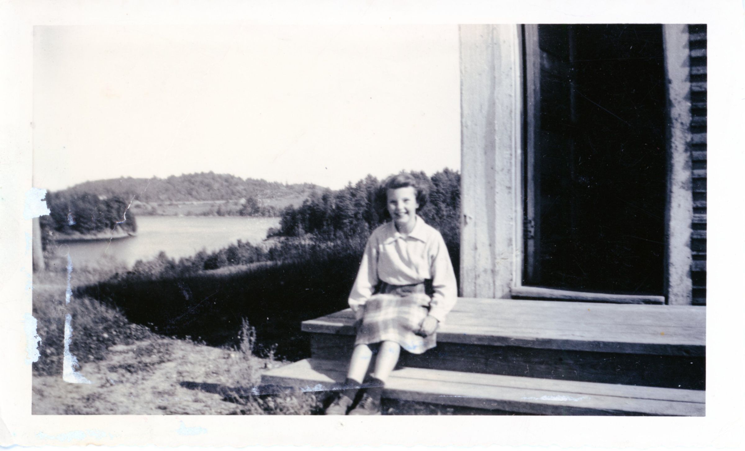 Preston District School, Edmunds, Maine; Calista Burr poses for a pictures on the steps of the Preston District School with a view of the Dennys River Narrows and Page's Mountain in the distance.