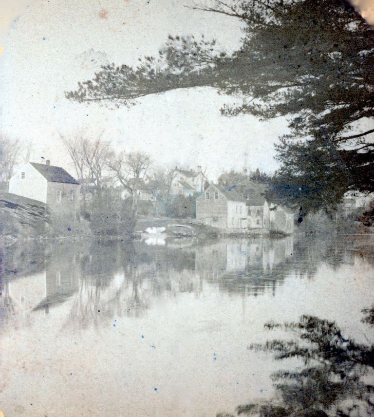          Shops and stores on the banks of the Dennys River, Dennysville, Maine.; D.K. Hobarts Drugstore is on the left, while Gardner's General Store and other shops line the bank of the Dennys River in this image taken around 1890 in Dennysville, Maine.  The Town Schoolhouse and the steeple of the Congregational church building are visible on the hill beyond.  Photograph courtesy of the Tides Institute in Eastport, Maine.
   