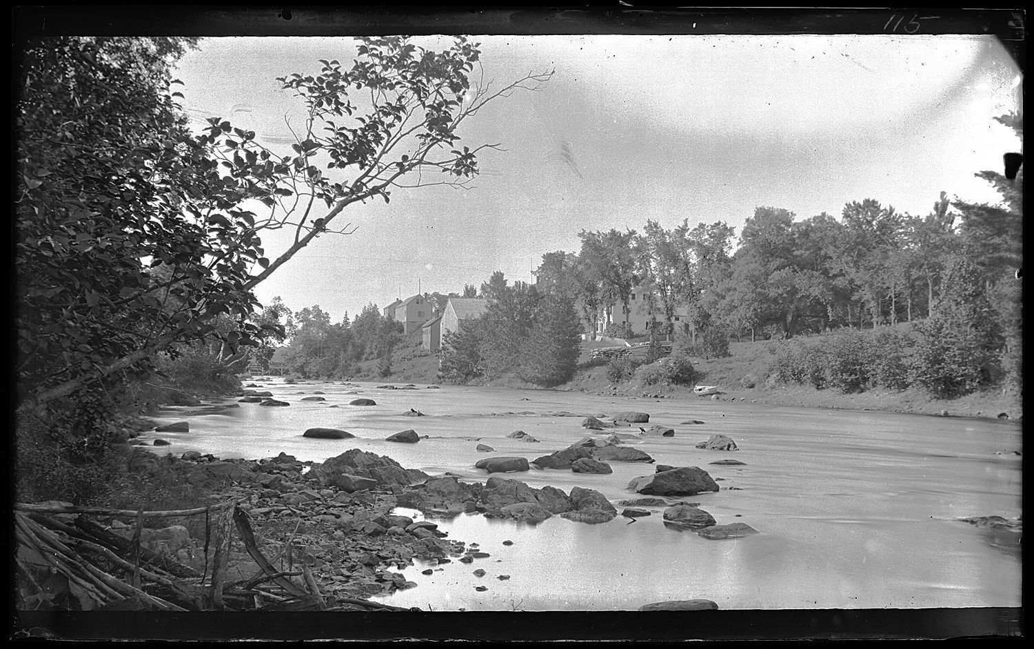 Dennys River with Store Hill in the distance.; View of the estuary on the Denny River from Edmunds at low tide, with a boat and buildings on Store Hill in Dennysville upstream opposite. Photograph by Dr. John P. Sheahan, c. 1885.