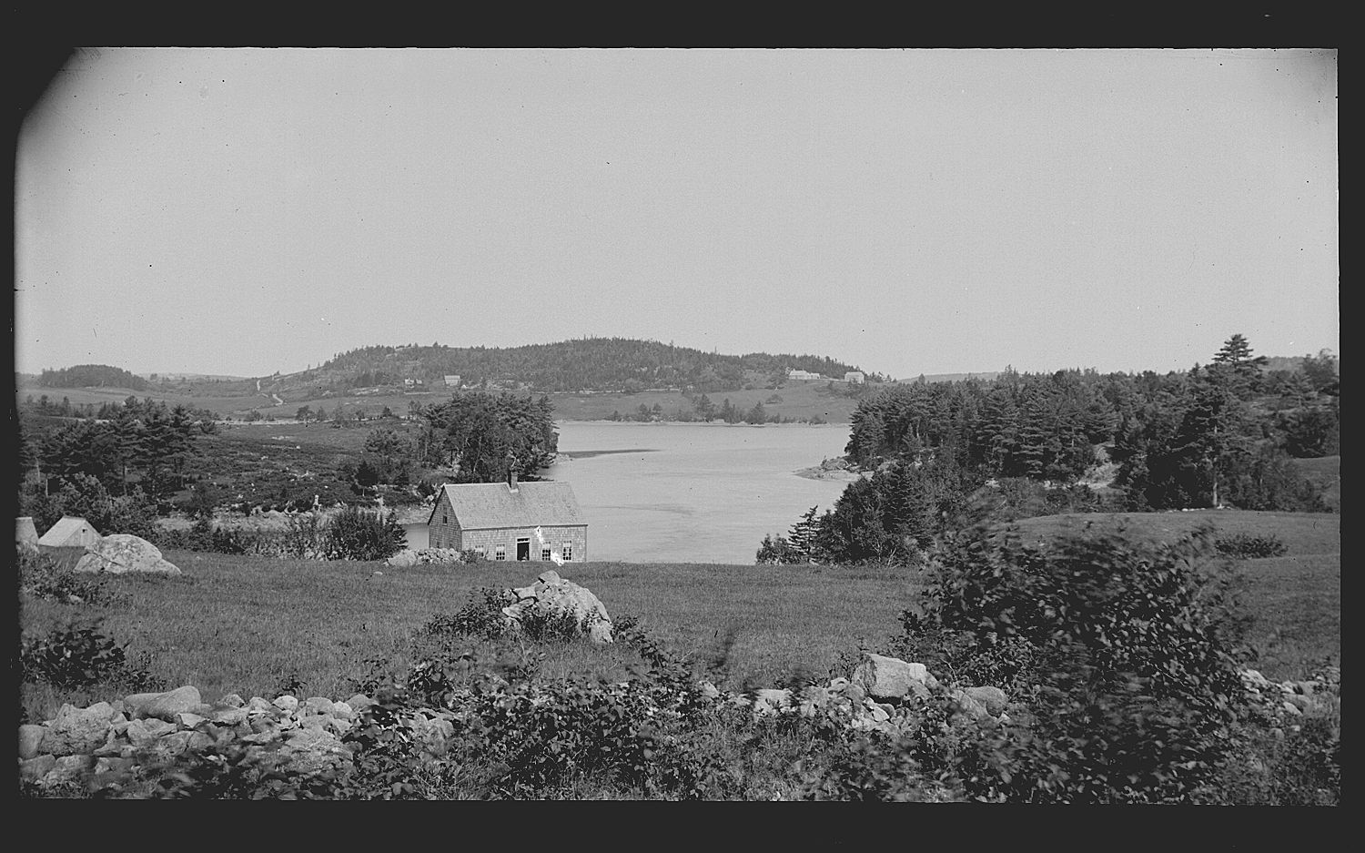 Dennys River Narrows with Hinckley Point and Pages Mountain in the distance; John Matthie's house stands in a field in Edmunds overlooking the Dennys River Narrows and Clark Point beyond. In the distance, across the Dennys Bay are Hinckley Point and above it Page's Mountain.