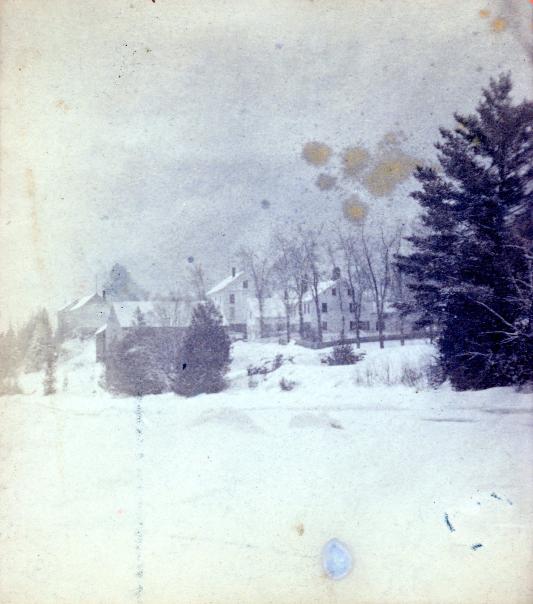 Riverside Inn and Livery Stable, Dennysville, Maine; John Allan's Livery stable is poised on the river bank across from the the Riverside Inn in this photograph from the early 1890's. John Allan's store is beside the Inn, while Peter E. Vose's Store and T.W. Allan's stores are visible at the top of Store Hill.
