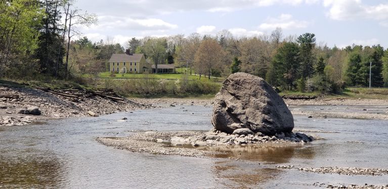          Rock Peter stands sentinel-like on the Edmund side of the Dennys River in eastern Maine, with the remains of T.W. Allan's wharf visible to the left, and the Lincoln House in the distance.  As part of the bedrock, Rock Peter served as the origin or starting point for all of the early surveys of the local area.
   