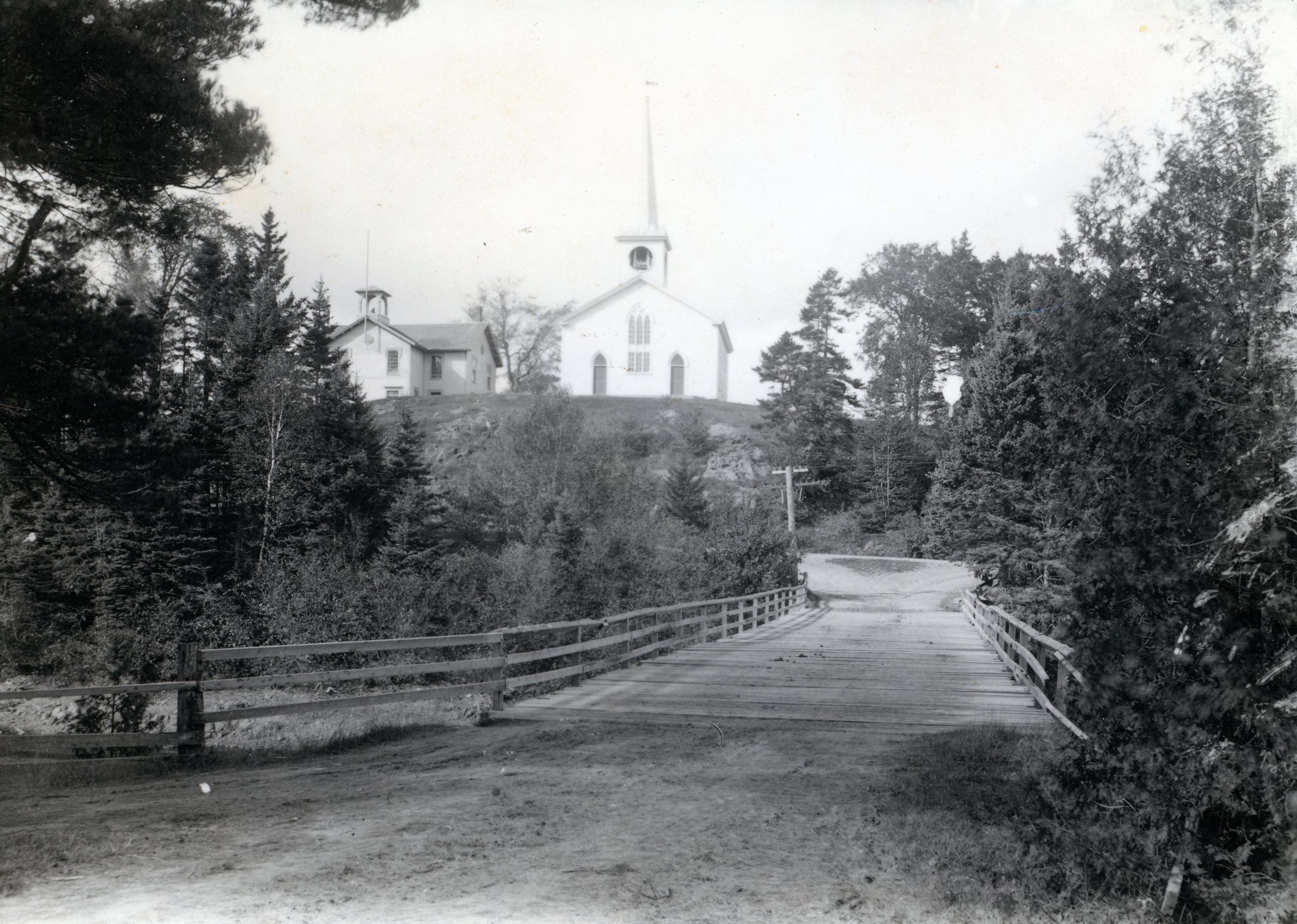 View of Lower Bridge Between Edmunds and Dennysville, c. 1910; The Congregational Meetinghouse and schoolhouse in Dennysville are seen above the Lower Bridge on Meetinghouse Hill