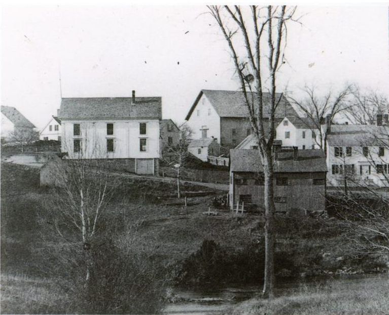          Shops and businesses on Store Hill in Dennysville, c. 1890.; Lyman K. Gardner's blacksmith shop occupies the center of this image on the banks of the Dennys River as seen from the Edmunds side of the river.
   